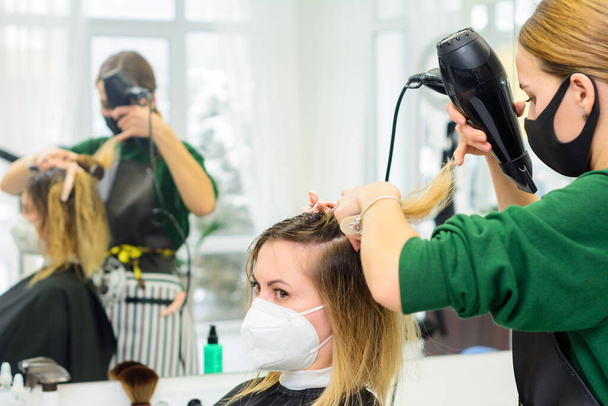 El estilista utiliza un secador de pelo para peinar el cabello después de la coloración. nuevo - Foto, imagen