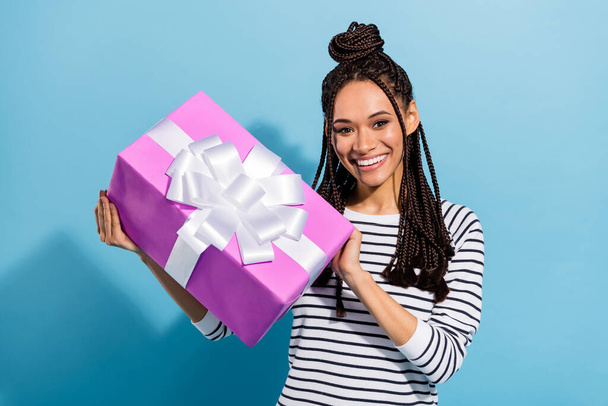 Photo portrait of girl with dreadlocks giving wrapped gift box birthday party smiling isolated pastel blue color background - Foto, Imagen