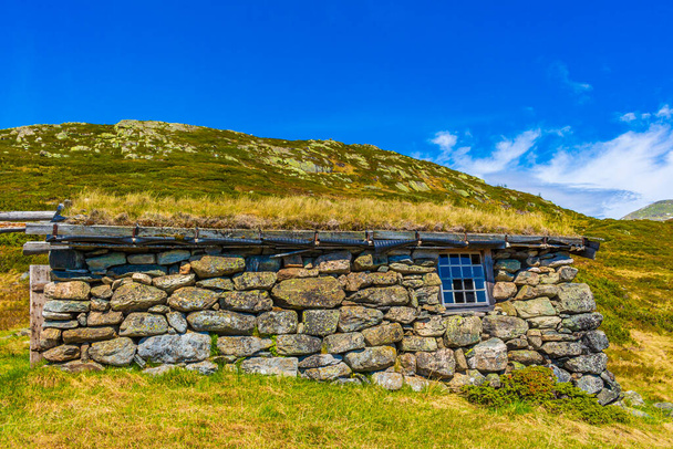 Amazing old stone house at Vavatn landscape panorama view with mountains with snow during summer in Hemsedal Norway. - Photo, Image