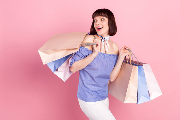 Foto portrét ženy na nákupy o víkendu vedení tašky hledá copyspace izolované na pastelové růžové pozadí - Fotografie, Obrázek