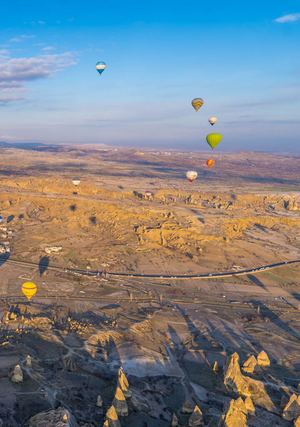 Urgup, Turquía - 19 de marzo de 2021 - plano vertical de los paisajes de Capadocia con chimeneas de hadas, montañas, formaciones rocosas, globos aerostáticos y la ciudad de Urgup - Foto, imagen