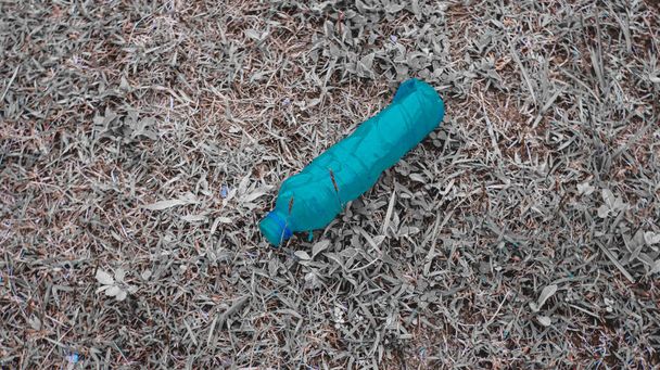 Großaufnahme einer gebrauchten Plastikflasche, die auf den Boden eines Waldes geworfen wurde, neben irgendeinem anderen Müll, wie gebrauchte Konservendosen und Plastikbehälter, Zeichen der Zufälligkeit gebrauchte Plastikflaschen, die auf einer Wiese zurückgelassen wurden - Foto, Bild