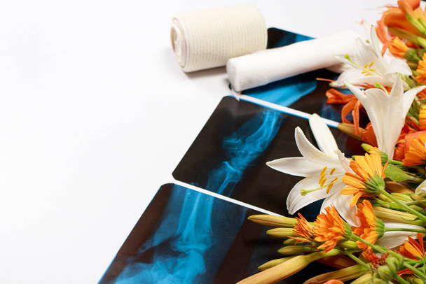 Üdvözlőlap virágokkal és röntgensugarakkal a traumatológus, radiológus, oszteopata napjára, fehér alapon szöveges szöveggel - Fotó, kép