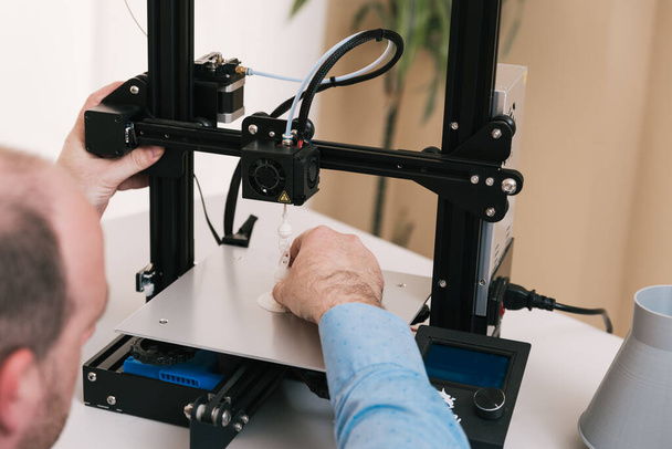 Jonge ingenieur in het lab die een 3D-printcomponent aanpast - Foto, afbeelding