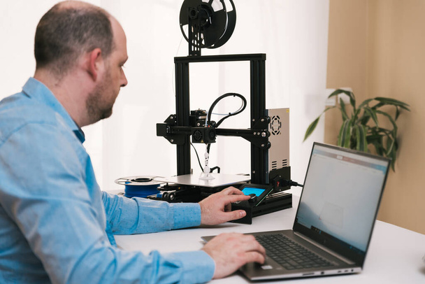 Молодой инженер в лаборатории настраивает компоненты 3D принтеров - Фото, изображение