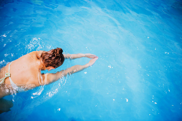 Κολυμπάει στην πισίνα, μια γυναίκα κολυμπάει στην πισίνα. - Φωτογραφία, εικόνα