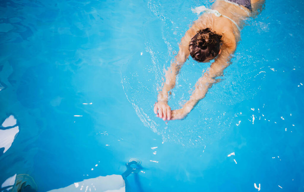 Mavi berrak su havuzunda yüzen bir kadın. - Fotoğraf, Görsel