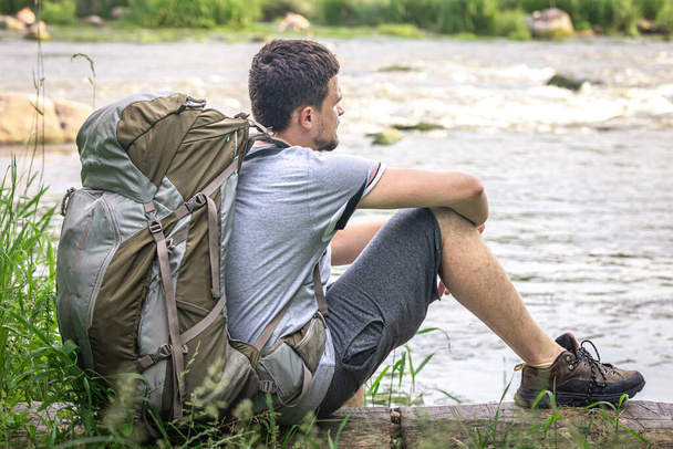 A tourist with a large backpack sat down to rest near the river. - Photo, Image