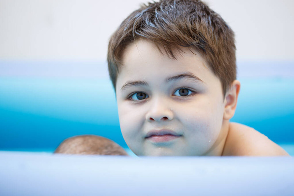 Портрет. Шестилетний мальчик в детском надувном бассейне. избирательный фокус. низкая глубина фокусировки. - Фото, изображение