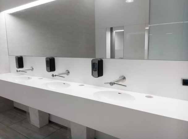 Egyszerű hatékonyság a modern fehér belső nyilvános mosdó több mosogató, csapok, szappanadagoló és tükör - Fotó, kép