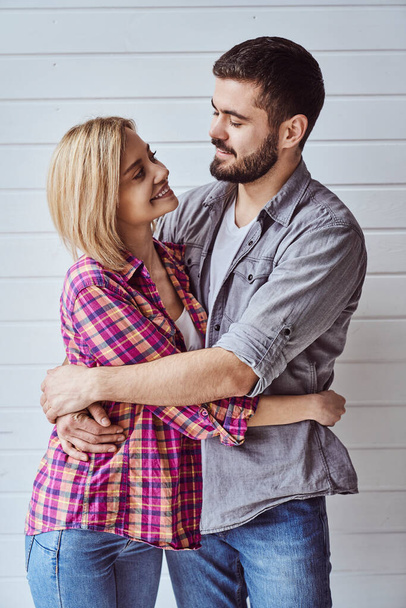 Portrait de jeune couple aimant joyeux souriant regardant la caméra et s'embrassant sur fond clair - Photo, image