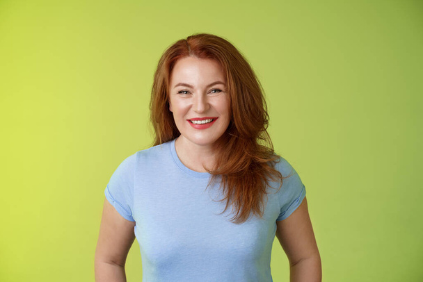Cheerful kind happy redhead middle-aged mother look caring delighted smiling broadly gaze admiration joy stand blue t-shirt green background amused enthusiastic expression - Fotografie, Obrázek