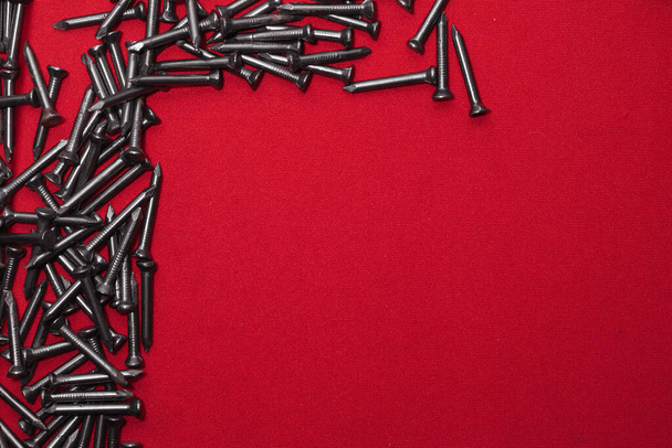 Template for advertising poster, made with steel nails on a red background, leaving space for text, upper left corner - Foto, Imagem