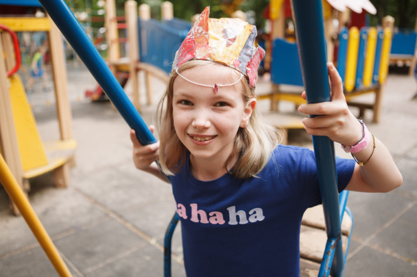 Charming happy child smiling to the camera, sitting on a swing on playground - Photo, Image