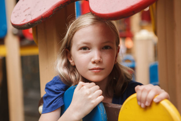 Sad young girl sitting alone on playground - Photo, Image