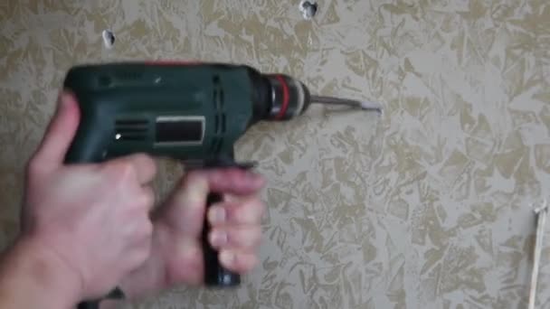 Las manos masculinas hacen agujero usando taladro eléctrico con broca de torsión - Metraje, vídeo