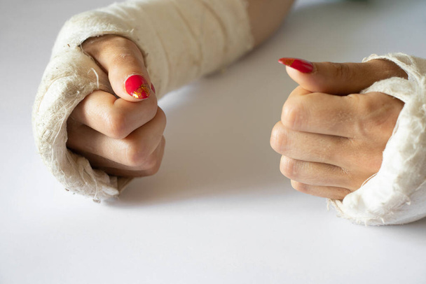 two female hands with broken wrists after falling from a bicycle in a cast on an isolated background, hands in a cast - Photo, Image