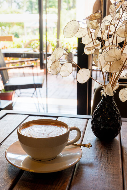 Een kop koffie op houten tafel in een café - Foto, afbeelding