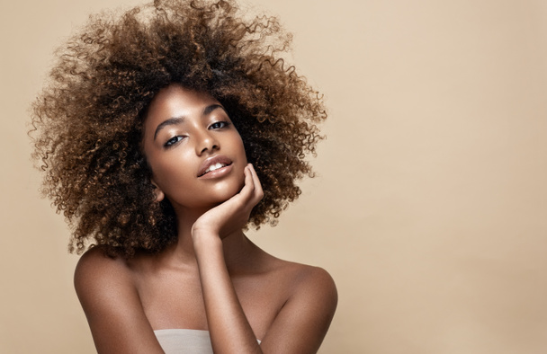 Ομορφιά πορτρέτο της αφρικανικής Αμερικής γυναίκα με καθαρό υγιές δέρμα σε μπεζ φόντο. Χαμογελαστή ονειρεμένη όμορφη αφρο κοπέλα.Σγουρά μαύρα μαλλιά - Φωτογραφία, εικόνα
