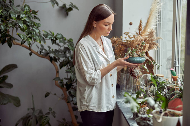 kavkazský sebevědomý šťastný florista pracuje s kompozicí ze skleněných kamenů a rostlin v botanické dílně - Fotografie, Obrázek