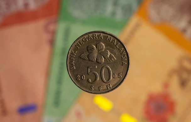 Dinero, monedas de 50 sen en el fondo borroso del billete de Ringgit Malasia, enfoque seleccionado. Concepto de Negocios, Finanzas, Economía e Inversiones. - Foto, imagen