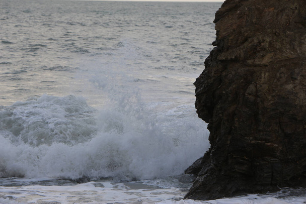 Atlanti vihar hullámok zuhannak le és mossák át a köveket és homokot a Carlyon öbölben Cornwallban, Anglia délnyugati partjainál. - Fotó, kép