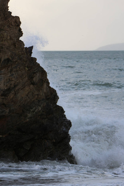 Κύματα καταιγίδας στον Ατλαντικό πέφτουν και πλένονται πάνω από βράχους και άμμο στην παραλία του κόλπου Carlyon στην Κορνουάλη στη νοτιοδυτική ακτή της Αγγλίας - Φωτογραφία, εικόνα