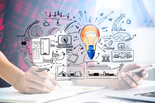 Woman hands writing down info from Smartphone, laptop on desk. Research process of new idea for start up. Colorful light bulb sketch. Concept of creativity and brainstorming - Фото, зображення