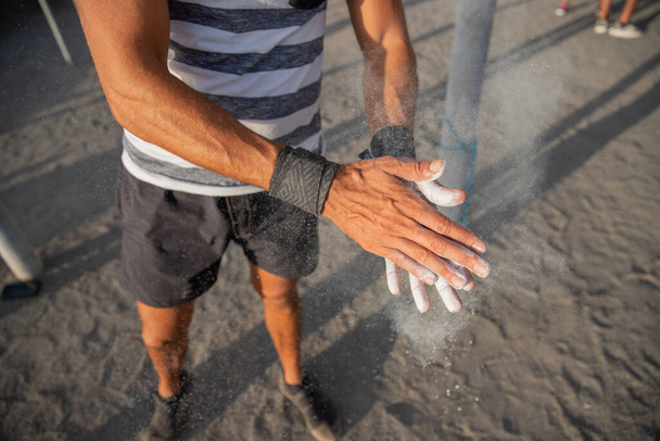 Ritratto delle mani di un atleta che applica la polvere di gesso per il sollevamento pesi per l'allenamento con i pesi - sportivo che utilizza attrezzature durante il concetto di allenamento - Foto, immagini