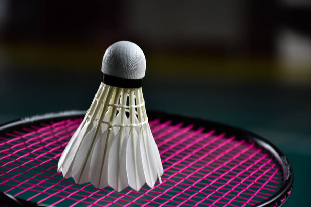 Vista de perto da raquete de badminton e do vaivém de badminton branco na quadra de badminton. foco suave e seletivo em shuttlecock. - Foto, Imagem