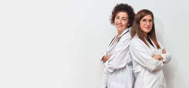 Portrait of two female doctors back to back looking at camera - Photo, Image