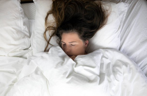 Fiatal lány szeplős alszik fehér lepedő felső nézet, Portré a gyönyörű fiatal nő alszik fehér ágyban a tiszta hálószobában, feküdt le közelkép - Fotó, kép