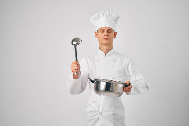 mężczyzna w kucharzy ubrania z rondla w jego rękach przygotowanie żywności lekkie tło - Zdjęcie, obraz
