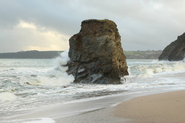A Carlyon öböl partján lévő magányos sziklafalon hatalmas hullámok csapkodnak, melyeket valahol az Atlanti-óceán mélyén egy vihar indít el, és Cornwall partjainál zuhannak le, Anglia délnyugati részén. - Fotó, kép