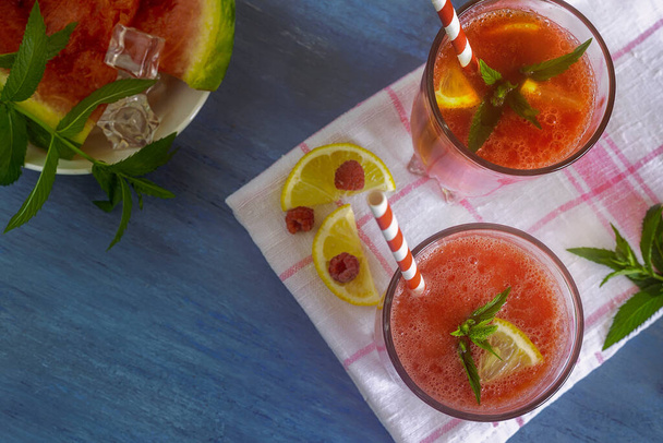 Friss görögdinnye lé málnával és citrommal egy pohárban. Görögdinnye és málna szeletek az asztalon. Első látásra. A természetes táplálkozás fogalma. - Fotó, kép