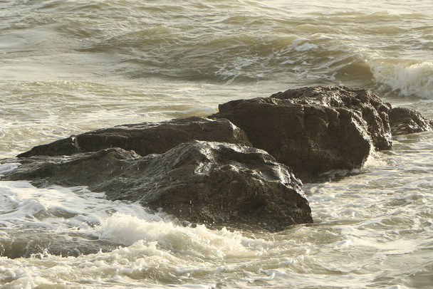 Olas que se estrellan sobre rocas y suben a la playa de Carlyon Bay a las afueras de St Austell, Cornwall, Inglaterra, tras una tormenta lejos del mar en el océano Atlántico - Foto, Imagen