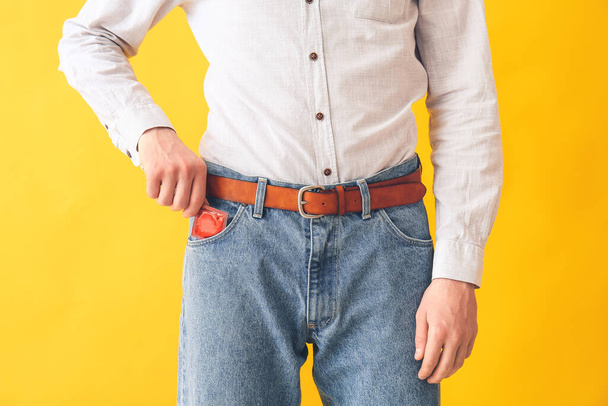 Man putting condom into pocket of jeans on color background - Foto, immagini