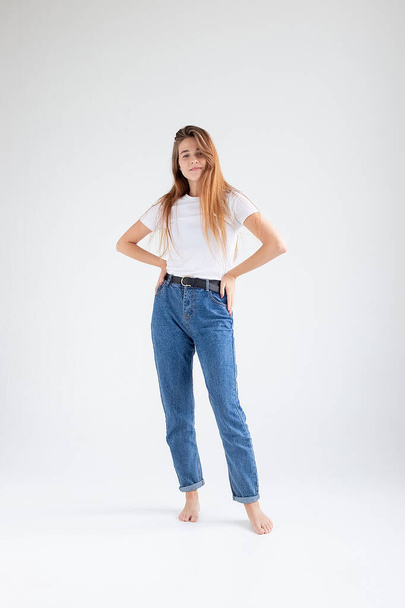 young caucasian pretty girl with long hair in t-shirt, blue jeans at studio - Photo, image