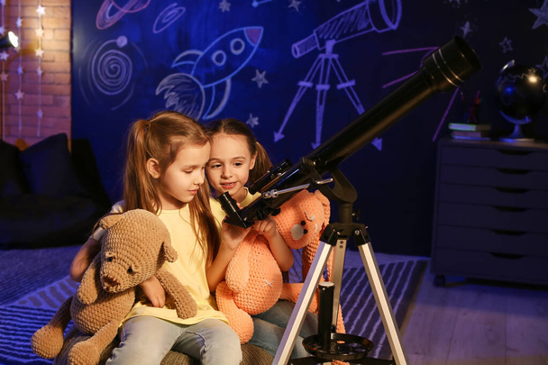 Симпатичні маленькі сестри з телескопом дивиться на зірки ввечері
 - Фото, зображення