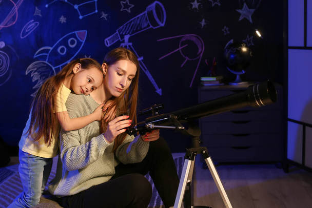 Sevimli küçük kız ve teleskoplu annesi akşamları yıldızlara bakıyor. - Fotoğraf, Görsel