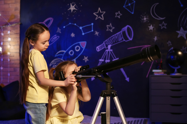 Симпатичні маленькі сестри з телескопом дивиться на зірки ввечері
 - Фото, зображення
