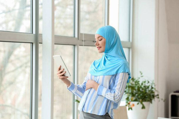 妊娠中のイスラム教徒の女性はオフィスでタブレットコンピュータを使用して - 写真・画像