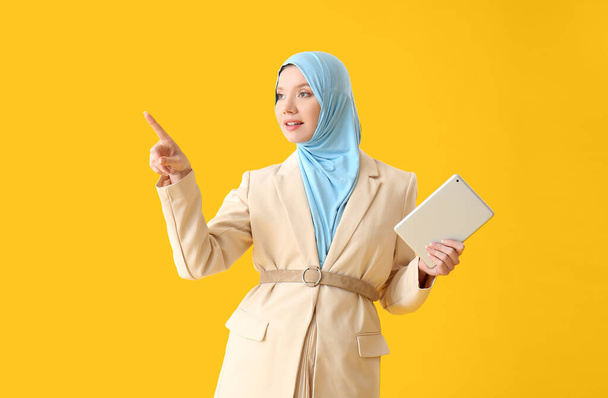 Вагітна мусульманка вказує на щось на кольоровому фоні. - Фото, зображення
