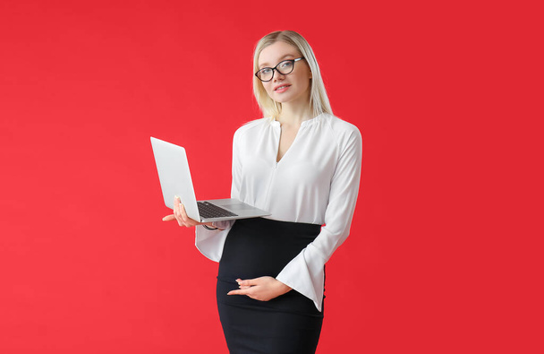 Pregnant young woman with laptop on color background - Foto, imagen