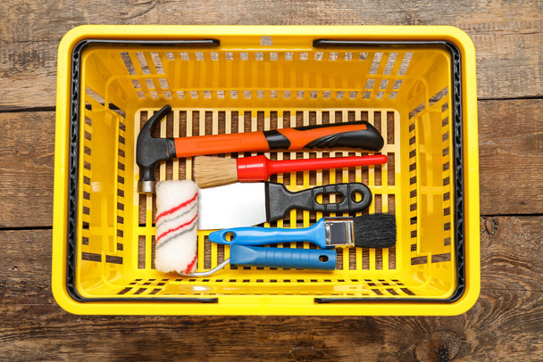 Cesta de compras con herramientas de trabajo sobre fondo de madera - Foto, imagen