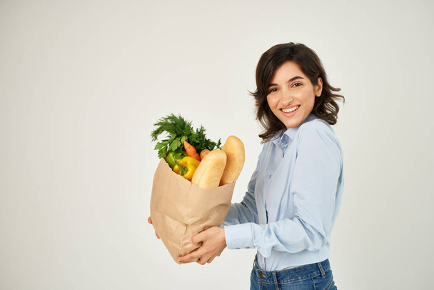 brunette in a blue shirt food bag vegetables healthy food - Fotografie, Obrázek