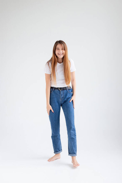 giovane caucasica bella ragazza con i capelli lunghi in t-shirt, blue jeans in studio - Foto, immagini