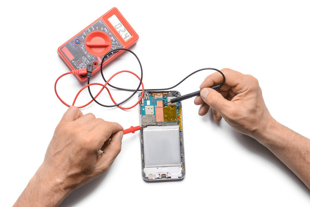 Male technician repairing damaged mobile phone on white background - Photo, Image