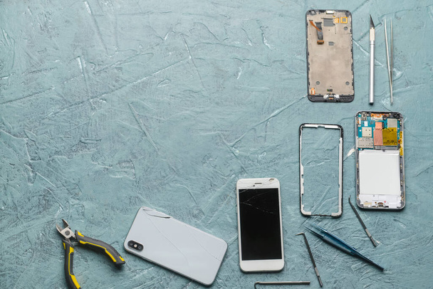Disassembled mobile phones with technician tools on color background - Foto, Imagen