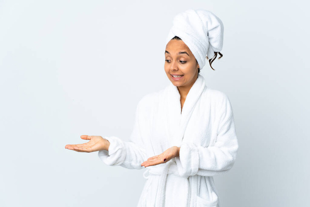 Jovem mulher em roupão de banho sobre fundo branco isolado com expressão surpresa ao olhar lado - Foto, Imagem